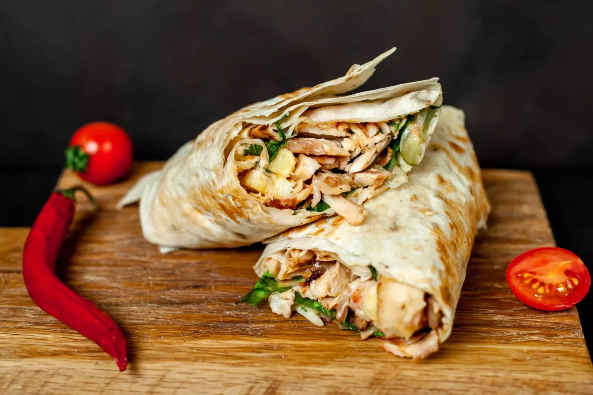burrito-wraps-with-chicken-vegetables-cutting-board-against-background-concrete-mexican-shawarma